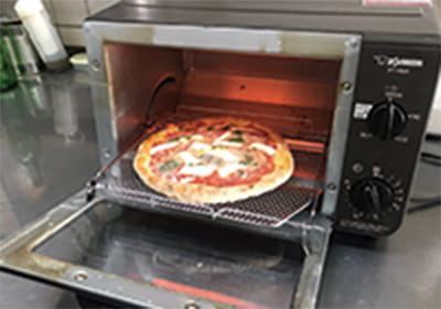 ピザをオーブントースターに入れている写真